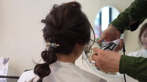 Male hairdresser ironing a woman's hair