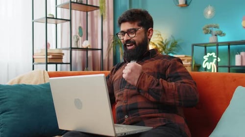 Man Cheering Success on Laptop While Sitting at Home