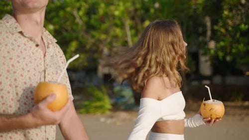 Pretty Woman Talks to Boyfriend Kiss Walking on Tropical Beach Smiling Couple Enjoy Holidays Drink