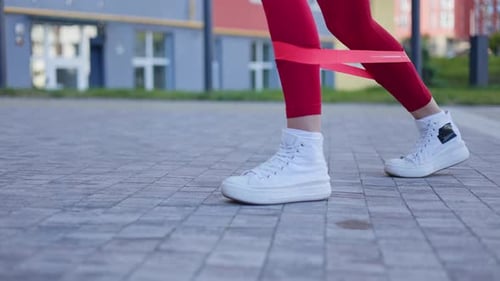 Woman Stretching Legs with Resistance Band on Walkway