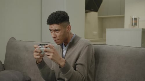 Enthusiastic Young Adult Playing Video Game on Sofa