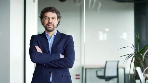Portrait of a smiling businessman in a formal suit standing in a modern business office..