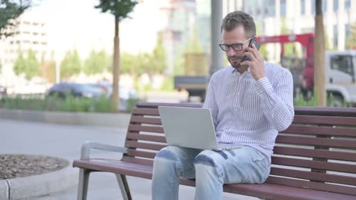 Man on Laptop Speaks on Cell Phone
