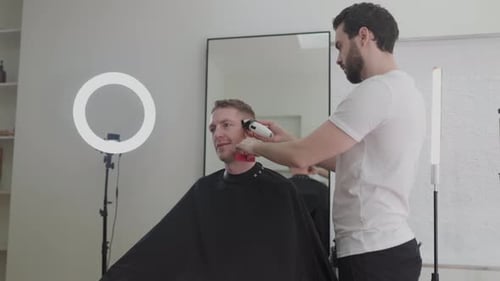 Man Getting Haircut at Salon, Barber Using Clippers