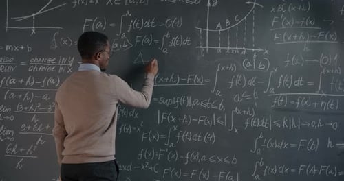 Person Writes Math Equations on Chalkboard