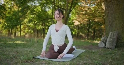Young Beautiful Athletic Woman in Sportswear Doing Stretching and Warming Up in the Park Near a Tree