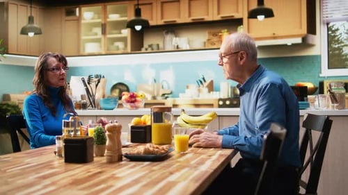Senior Couple Chatting Over Breakfast at Kitchen Table