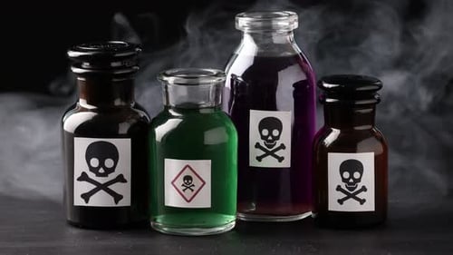 Bouteilles de poison avec des panneaux d'avertissement et de la fumée sur une table sombre sur fond noir