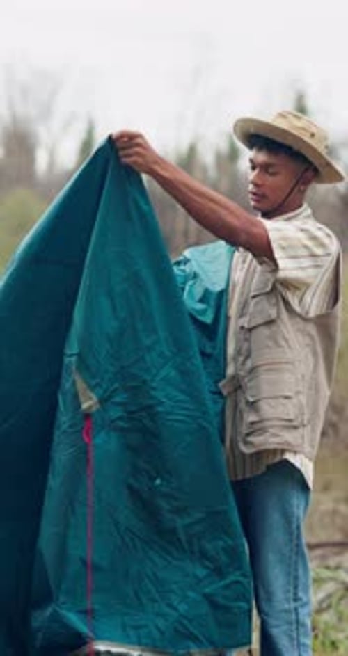 Camping, getting ready and tent with man in nature for adventure, holiday or weekend vacation