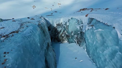 Aerial View of Glacial Crevasse in Snowy Mountains