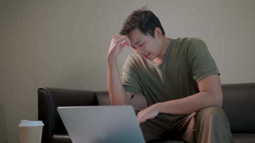 Overwhelmed by Work a man, exhausted and frustrated, works on his laptop late at night, overwhelmed