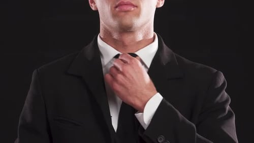 Closeup of a Handsome Guy Adjusting His Tie with Confidence
