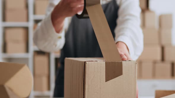Packing A Box A Parcel Warehouse Worker Packs A Box With Brown Tape ...