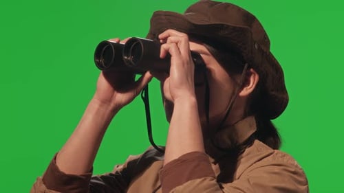 Female Tourist Looking through Binoculars on Green Background