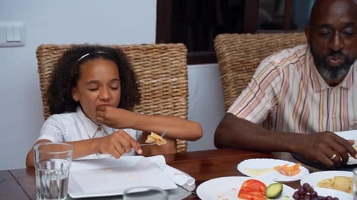 Child Eating Meal at Table with Family
