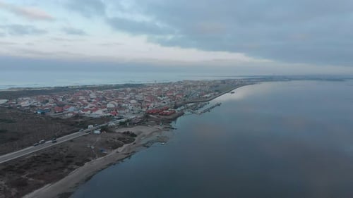 Aerial view of a small village between the ocean and the river on a cloudy day. Amazing bay on the h
