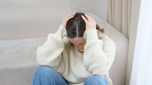 Woman Sitting on Floor Upset with Hand on Head