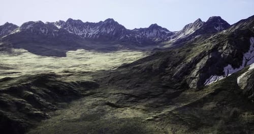 Mountain Landscape with Rugged Terrain and Snow Capped Peaks Under Clear Sky