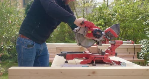 Adult Uses Powered Miter Saw To Cut Wood