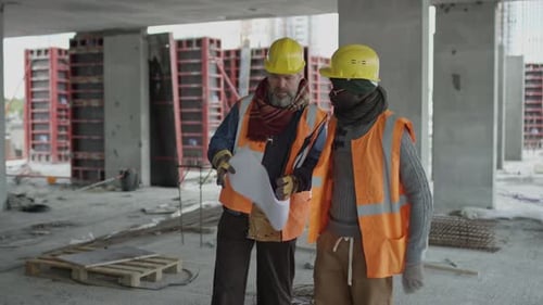 Construction Workers Reviewing Blueprints on Site