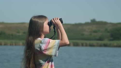 Kid Girl Tourist in Summer Camp on River Bank Looking Through Binoculars