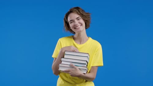 Clever Student Woman Holds Stack of University Books From College Library on Blue Background