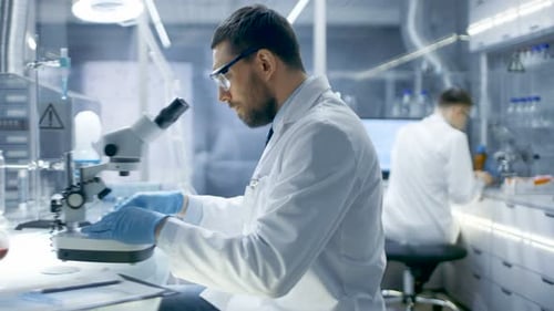 Man Scientist Using Microscope in Modern Laboratory Setting