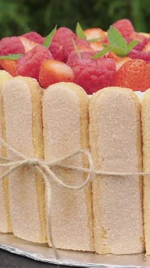 Berry raspberry and strawberry pie with mint. Savoiardi cookies. Rotation. Close-up. Vertical video.