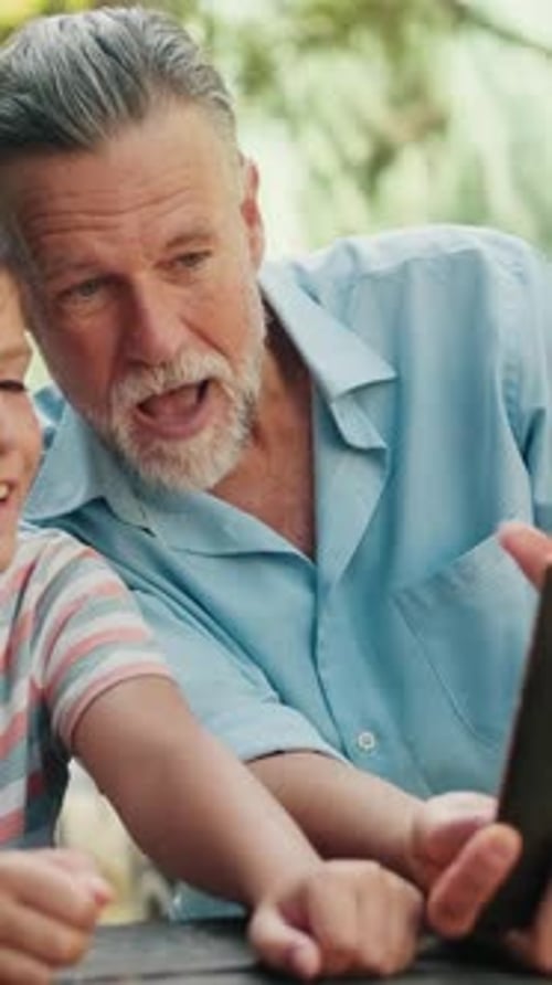 Vertical video, Grandfather And Grandson Video Chat At Park