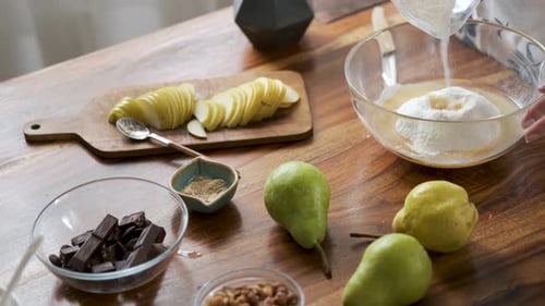 close-up of pear and chocolate on the table, a woman preparing dough for a pie