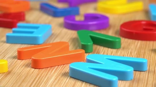 Multicolored letters rotate on a wooden background. The concept of learning, school or college