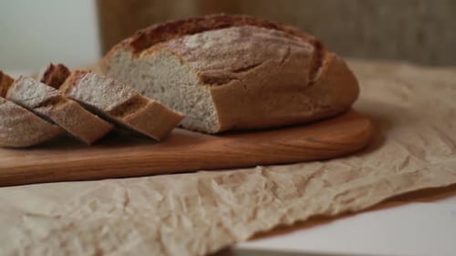 Fresh bread loaf sliced on wooden cutting board