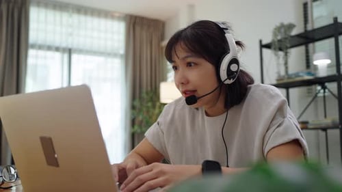 Woman Working on Laptop with Headset at Home
