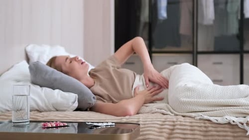 Woman Lying in Bed with Stomach Pain