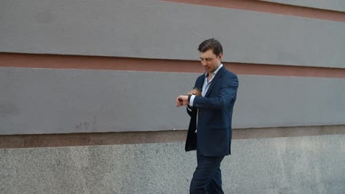 Glücklicher Geschäftsmann, der Smart Watch in der City Street benutzt. Lächelnder Geschäftsmann trinkt