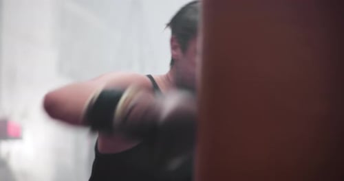 Man Powerfully Training with Punching Bag in Gym