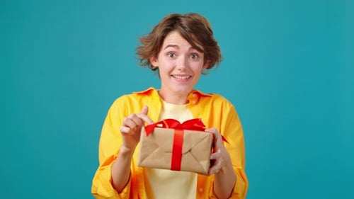 Woman Smiles Holding Birthday Present on Blue Background