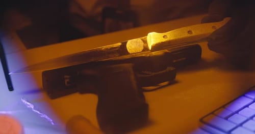 Handgun and Knife on Desk in Low Light