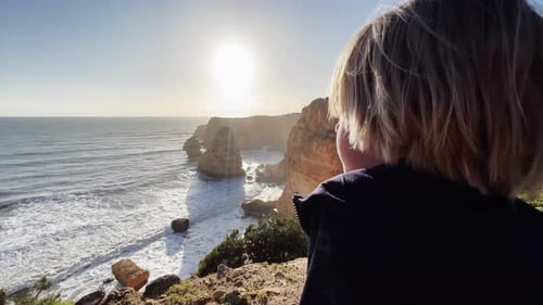 young boy standing on a cliff and looking down at the ocean in Portugal