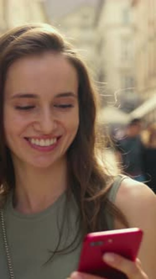 Une jeune femme joyeuse utilisant joyeusement son smartphone dans un cadre urbain lumineux et ensoleillé