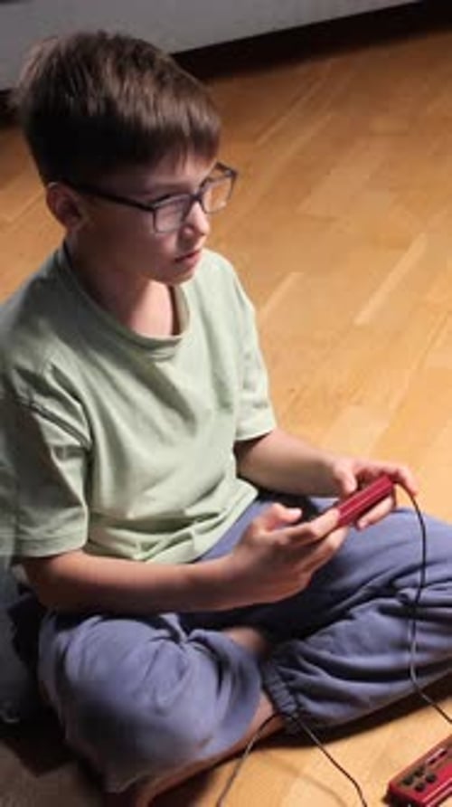 Boy with Glasses Plays Handheld Video Game