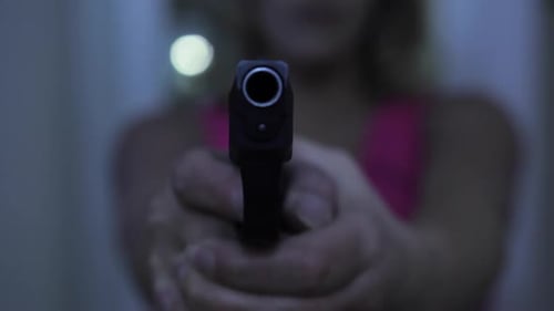 Handgun Aimed at Camera in Dark Setting