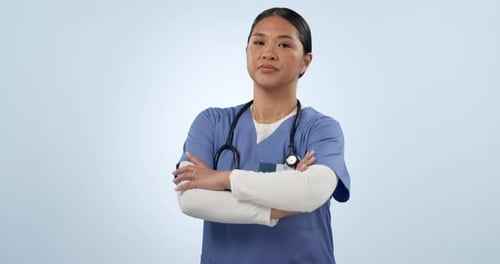 Woman, face and serious doctor in studio with arms crossed for expert healthcare services on blue
