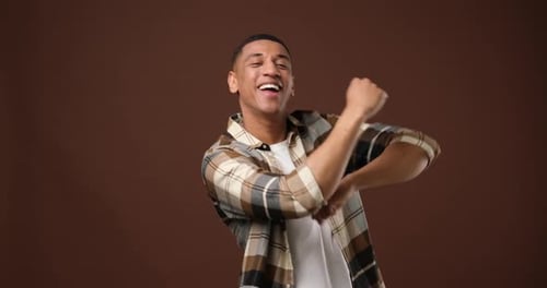 Happy Young African American Man Dancing Over Brown Studio Background