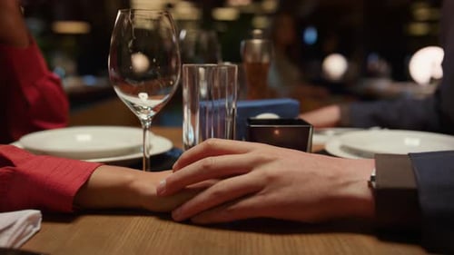 Romantic multiethnic couple holding hands on dinner date in stylish restaurant
