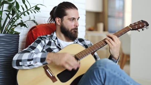 Man Plays Guitar In Home Setting