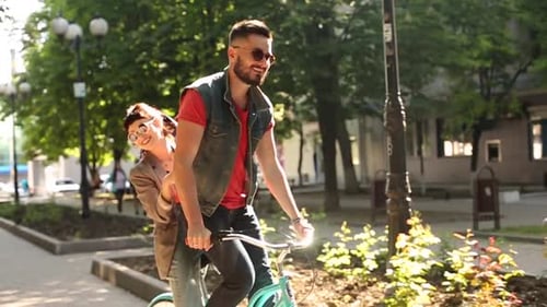 Jovem casal andando de bicicleta juntos no parque Namorado romântico andando de bicicleta com namorada feliz