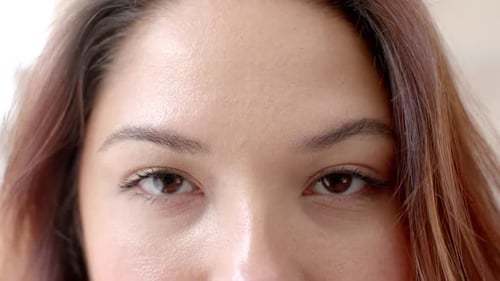 Portrait close up of eyes of happy biracial woman smiling at home, copy space, slow motion
