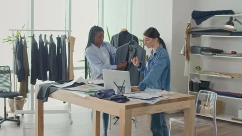 Two Women Fashion Designers Collaborating in Studio