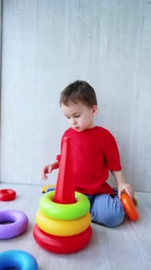 Un encantador niño caucásico con una camiseta roja se sienta en el suelo.